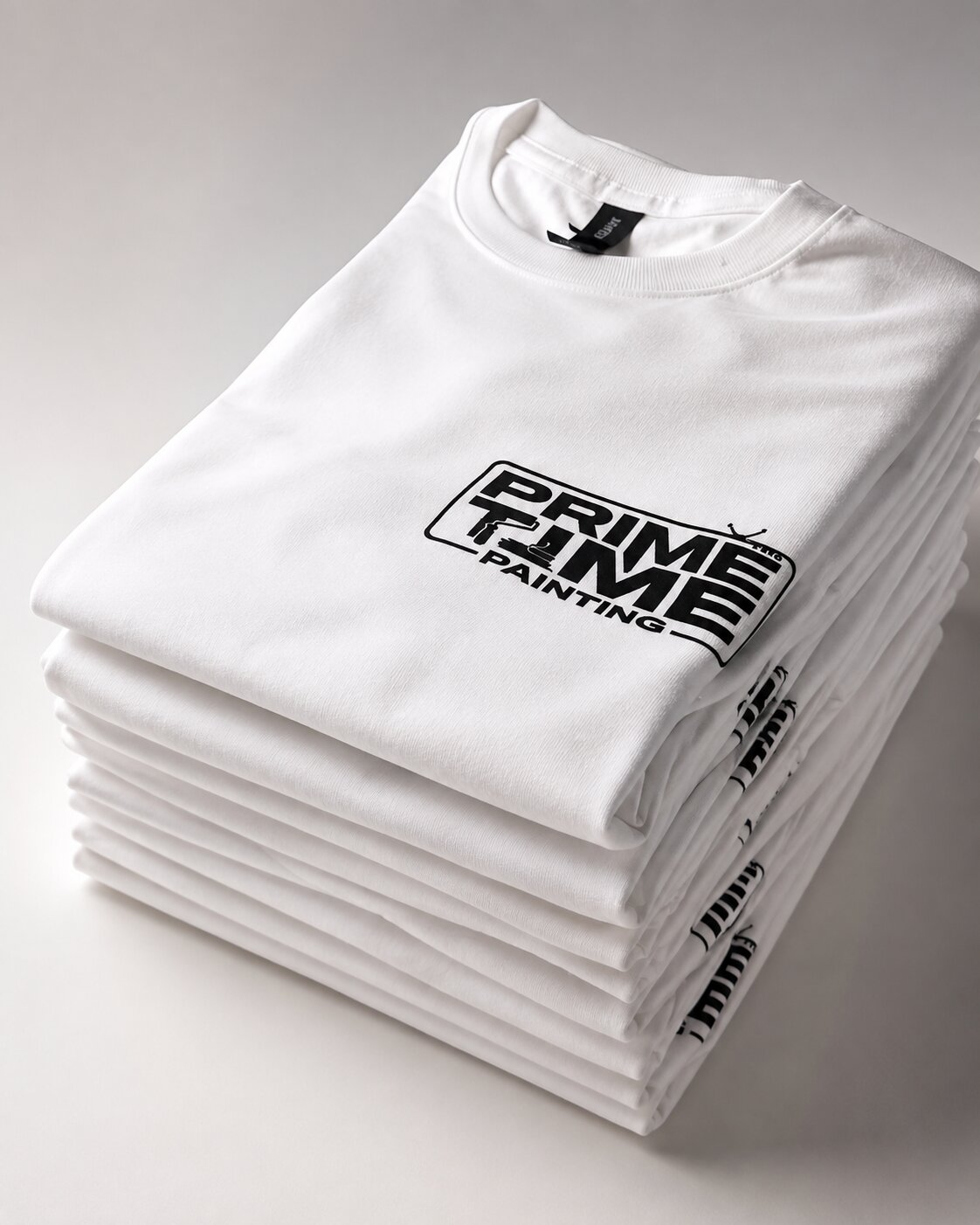 Prime Time Painting crew tee stack — black chest-logo screen print on a tall stack of folded white tees