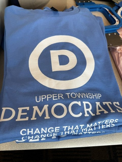 Carolina blue tee with the Democratic Party D logo and 'UPPER TOWNSHIP DEMOCRATS — Change That Matters' screen-printed on the front